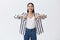 Indoor shot of amazed carefree beautiful woman in striped blouse and jeans, laughing out loud from happiness, pointing