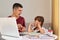 Indoor shot of angry aggressive father screaming at his daughter while helping her to do homework, family posing in room at home