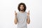 Indoor shot of anxious believing eastern bearded man with afro hairstyle, raising crossed fingers and grimacing from