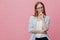 Indoor shot of attractive young lady keeps hands partly crossed, looks seriously at camera, wears elegant shirt and trousers,