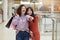 Indoor shot of casually dressed beautiful girls walking through mall carrying lots of shopping bags, pointing to somewhere, stand