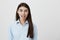 Indoor shot of childish woman sticking out her tongue, expressing happiness and being a little crazy, over gray