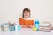 Indoor shot of clever smiling cute little girl with braids sitting at desk, holding book, reading interesting text, enjoying