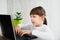 Indoor shot of cute dark haired female child looking at notebook, typing on keyboard