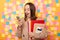 Indoor shot of extremely excited amazed young woman holding copybooks, paper folder and calculator, using smart phone, reading