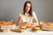 Indoor shot of frustrated sad woman with brown hair wearing white T-shirt sitting at table isolated over gray background, eating