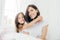 Indoor shot of good looking brunette mother with gentle smile and her small daughter gives hug, enjoy domestic atmosphere, pose ag