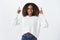 Indoor shot of happy and enthusiastic good-looking african american female with curly hair in sweater raising hands and