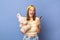 Indoor shot of happy joyful delighted teen girl wearing striped T-shirt and baseball cap holding cell phone and rabbit toy,