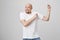 Indoor shot of happy positive bald man with beard, wearing white t-shirt and jeans being excited and overwhelmed with