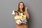 Indoor shot of hopeful woman with brown hair holding box with her personal stuff, hopes to get new job, posing with frowning face