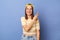 Indoor shot of joyful cheerful teen girl wearing striped T-shirt and baseball cap standing isolated over blue background, showing