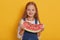 Indoor shot of little charming girl with portion of sweet watermelon in her hands, charming blonde modelposing  over