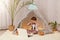 Indoor shot of little preschooler girl sitting in wigwam in front of notebook, having video call, covering eyes with palm, hiding