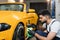 Indoor shot of male worker in overalls, washing the car wheels rims