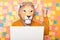 Indoor shot of man wearing orange sweater and paper lion mask posing isolated over yellow background, working on laptop, clenched