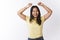 Indoor shot of optimistic happy and emotive young malaysian woman jumping playfully and laughing, grinning at camera