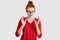 Indoor shot of outraged woman gestures angrily, has frowned expression, wears spectacles and red clothes, looks with