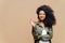 Indoor shot of pleasant looking curly woman has pleasant smile, makes okay gesture, excellent sign, gives approval, dressed in