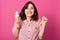 Indoor shot of positive energetic brunette raising hands, holding portion of ice cream, smiling sincerely, having pleasant facial