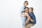 Indoor shot of positive happy family guy holding son with vitiligo on shoulders and cute kid on chest, smiling broadly