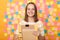 Indoor shot of positive optimistic woman student with brown hair in striped t shirt standing against yellow wall with memo cards,