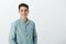 Indoor shot of positive outgoing male friend in casual shirt, smiling joyfully and expressing confidence, standing over