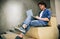 Indoor shot of young man with curly hair using laptop for chatting online with friends, browsing Internet, sitting on the stairs