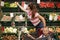 Indoor shot of young mother and daughter sitting in trolleyin supermarket, shopping for fresh fruit and vegetables in greengrocery