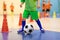 Indoor soccer young player with a soccer ball in a sports hall. Player in green uniform. Sport background.
