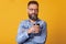 Indoor studio shot of magnetic successful man standing isolated over bright yellow background, having stylish haircut and bushy