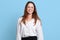 Indoor studio shot of successful cheerful executive standing  over light blue background, having positive facial