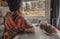 Indoor view of a woman looking and enjoying outside wooden mountain scenic place from interior of a camper. Tourist and travel