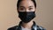 Indoors portrait close facial expression female face asian race woman ill serious girl in black protective medical mask