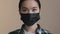 Indoors portrait close facial expression female face asian race woman ill serious girl in black protective medical mask