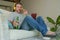 Indoors portrait of young happy relaxed and attractive man sitting at home sofa couch with headset and laptop listening to intern