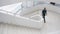 Indoors view of a modern building with men walking on staircase. Media. Beautiful completely white stairs of a business