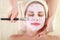 Indulge in Relaxation: Tranquil Portrait of a Woman Applying a Facial Mask at the Spa. Discover the serenity of self