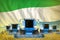 industrial 3D illustration of many blue farming combine harvesters on rye field with Sierra Leone flag background - front view,