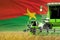 industrial 3D illustration of three green modern combine harvesters with Burkina Faso flag on rural field - close view, farming