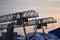 Industrial area. Outdoor crane trestle. Electric overhead traveling crane above the open warehouse and loading area at dawn. A smo