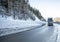 Industrial Black big rig semi truck with semi trailer driving on the winding winter dangerous slippery highway road with snow and