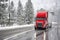 Industrial bonnet bright red big rig semi truck with dry van loaded semi trailer slipping slowly and carefully on a snowy winter