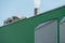 An industrial building and a chimney with white smoke against a blue sky. Air pollution from the smoke of a working factory.