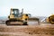 Industrial building construction site mini bulldozer levelling and moving soil during highway building