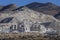 Industrial buildings for mining operation sits in front of large tailing piles in front of a mountain