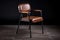 industrial chair with a leather or faux-leather seat, metal legs and wooden armrests