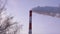 Industrial chimney stack at heat power station on background sky and bare trees