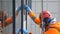 Industrial climber in bright suit and helmet washes windows at a height close up