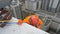 Industrial climber in orange suit and helmet prepares to descend from roof of multi-storey building for glass washing